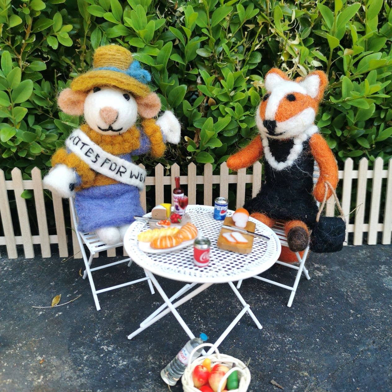 Knitted ornament of a woman in a suffrage dress with a banner on a gray background