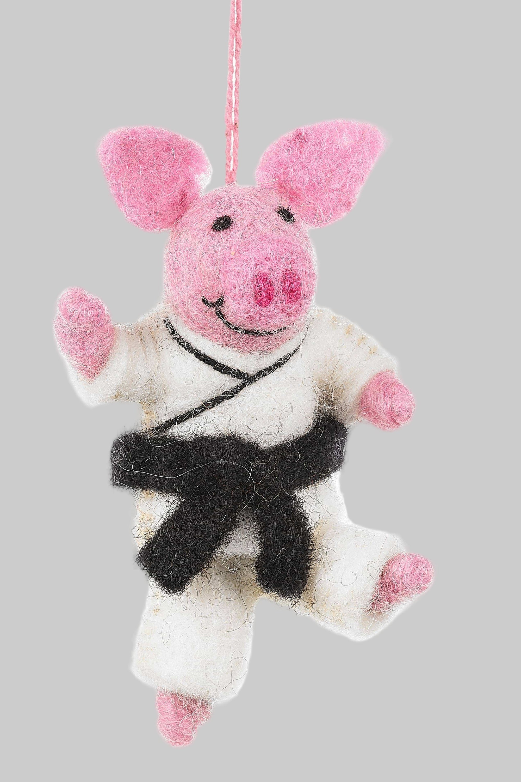 Pink pig plush toy with a black belt hanging on a white background
