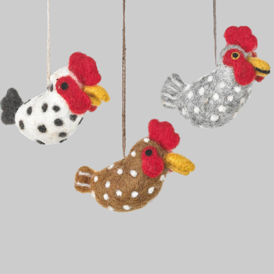 Three felt rooster ornaments hanging against a white background